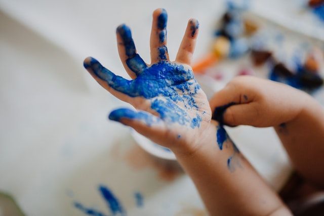 Blauwe verf op kinderhandje